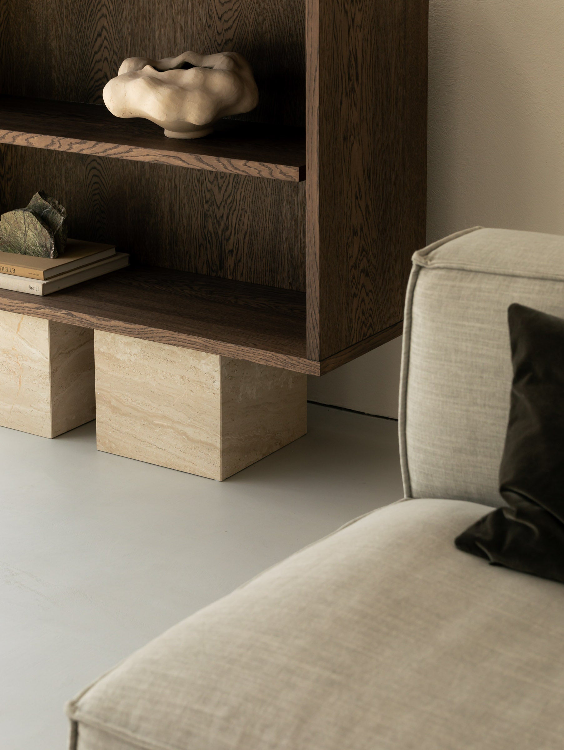 Un'common BLOCK Sideboard oak unit on Breccia marble block legs, styled with a ceramic vessel, a raw stone, and stacked books, beside a linen armchair.